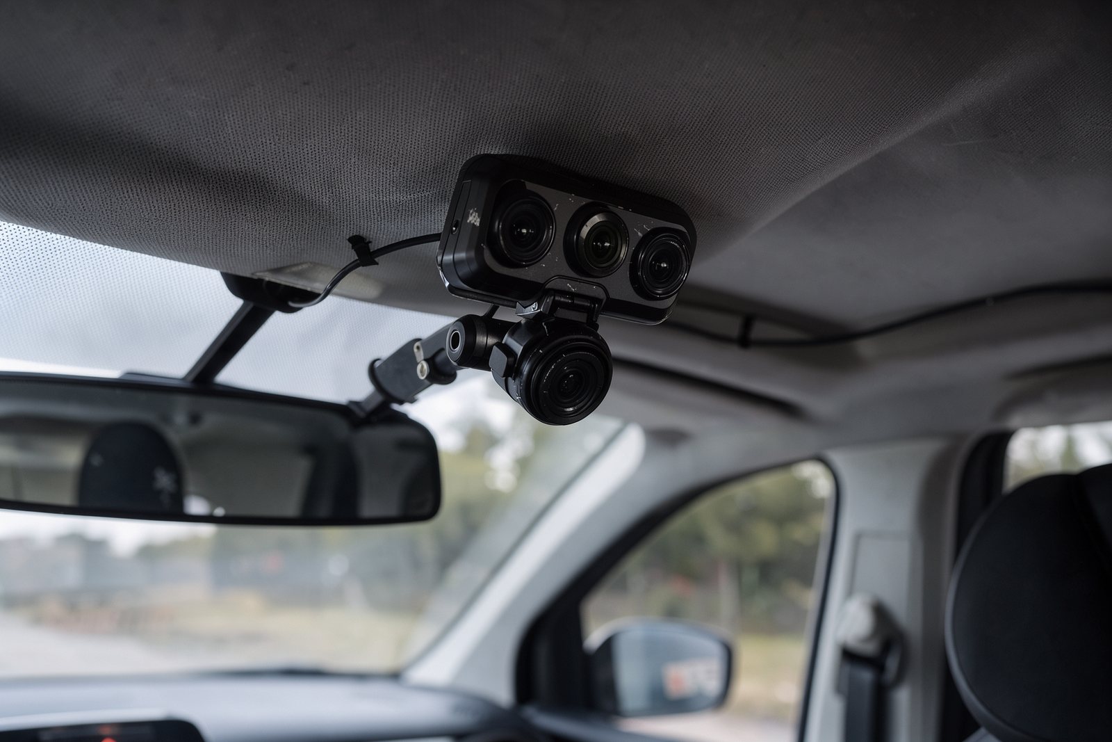 Detail einer hinter dem Rückspiegel montierten Dashcam mit Innenraumobjektiv